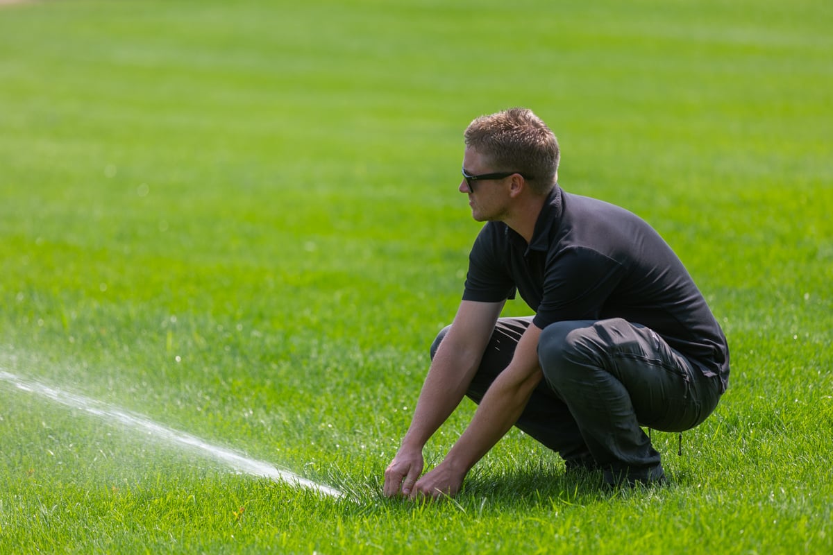 lawn care technician adjusting a lawn sprinkler