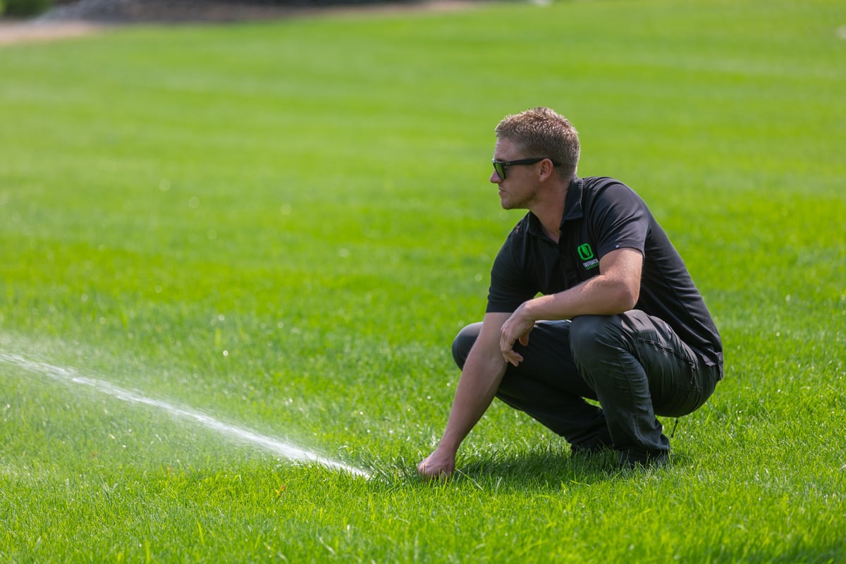 irrigation technician calibrating a lawn sprinkler head