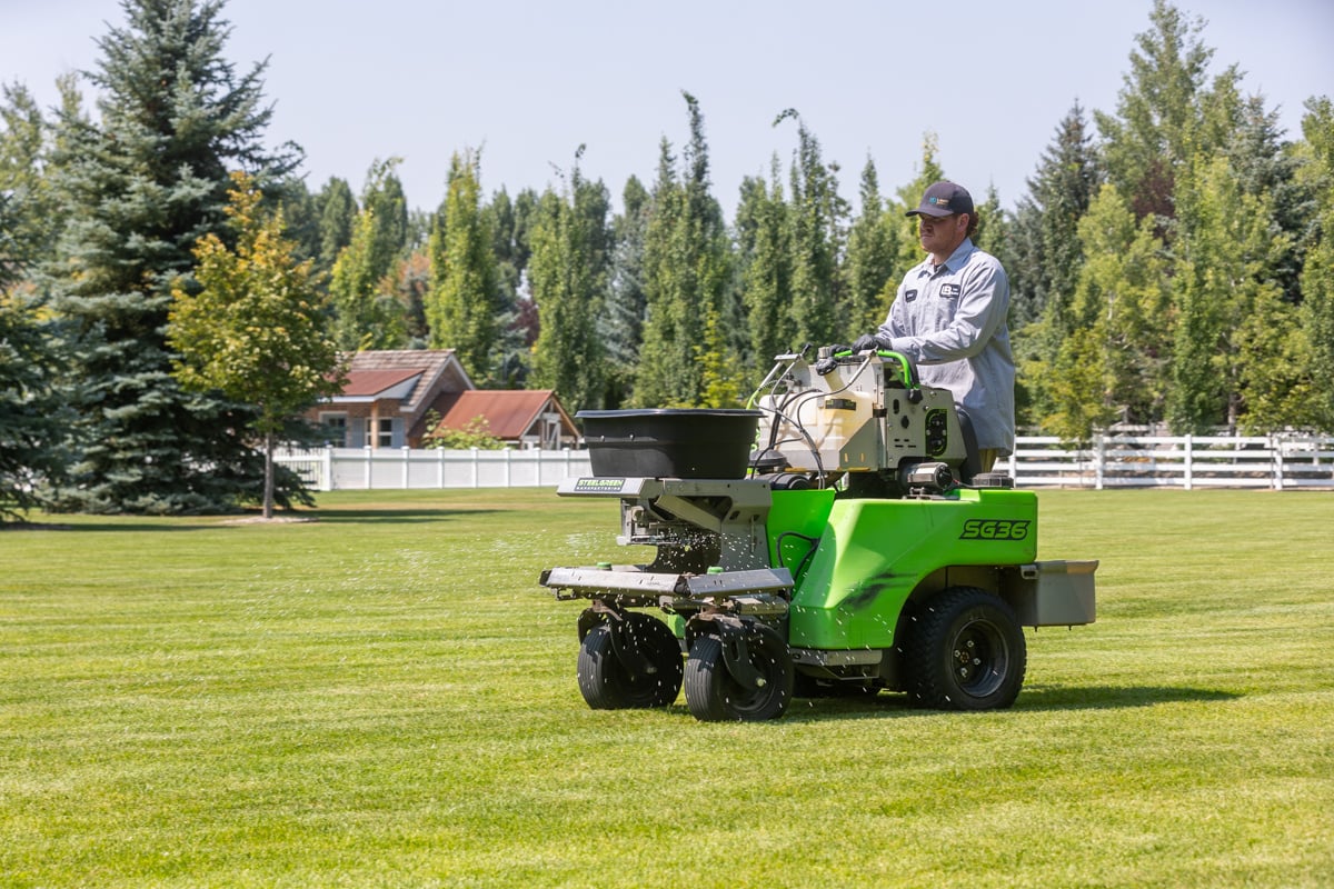 lawn care technician spreading granular fertilizer on a nice lawn