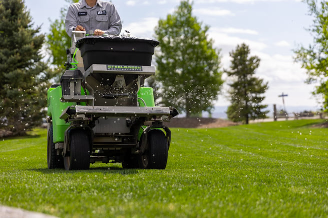 lawn care technician spreading granular lawn product on a nice idaho falls lawn